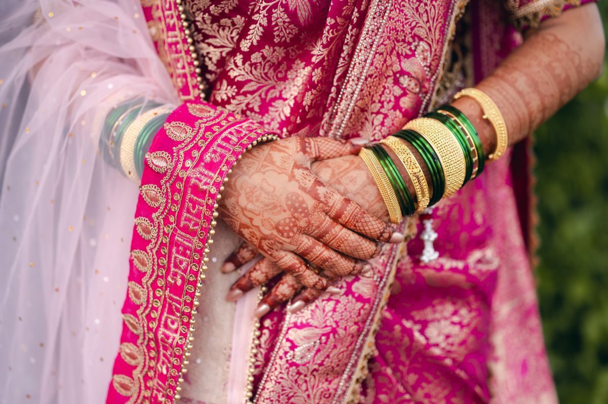 Bridal hands wearing traditional bangles with mehndi